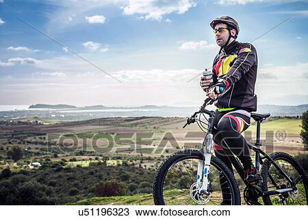 "Male mountain biker with water bottle on coastal path, Cagliari, Sardinia, Italy" View Large Photo Image Stock Image - "Male mountain biker with water bottle on coastal path, Cagliari, Sardinia, Italy". Fotosearch