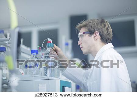 Stock Image - Male scientist checking experimental equipment in lab. Fotosearch