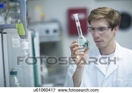Male scientist looking at flask in lab View Large Photo Image Stock Photo - Male scientist looking at flask in lab. Fotosearch