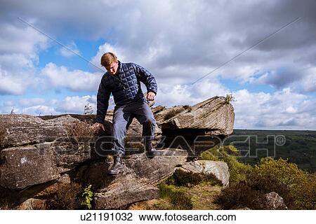 Stock Image - "Male teenage hiker stepping down rocks on Guise Cliff, Pateley Bridge, Nidderdale, Yorkshire Dales". Fotosearch