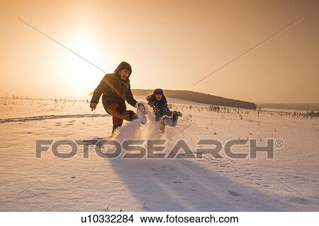 Picture - "Man and son kicking snow powder at sunset, Sarsy village, Sverdlovsk Oblast, Russia". Fotosearch