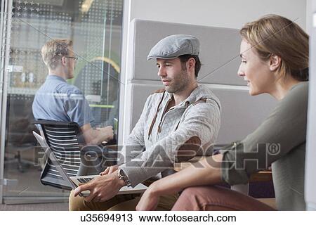 Stock Image - Man and woman looking at laptop in office meeting. Fotosearch