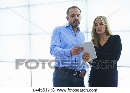 Man and woman using digital tablet against backlit wall panels View Large Photo Image Stock Image - Man and woman using digital tablet against backlit wall panels. Fotosearch
