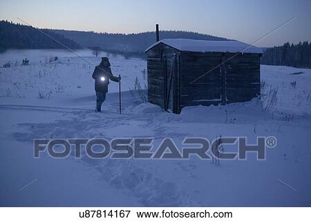 Stock Photo - "Man in snow covered landscape pointing torch at dusk, Sarsy village, Sverdlovsk Oblast, Russia". Fotosearch