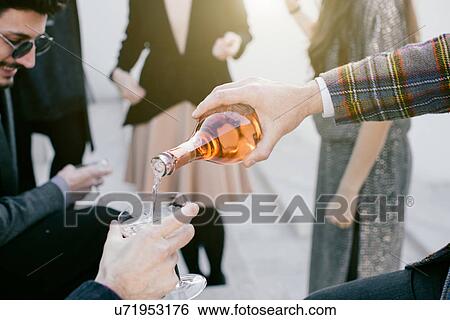 Man pouring drink into glass at party View Large Photo Image Stock Photograph - Man pouring drink into glass at party. Fotosearch