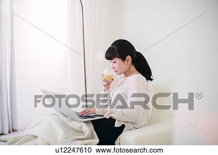 Mature businesswoman drinking orange juice whilst using laptop in hotel room View Large Photo Image Stock Image - Mature businesswoman drinking orange juice whilst using laptop in hotel room. Fotosearch