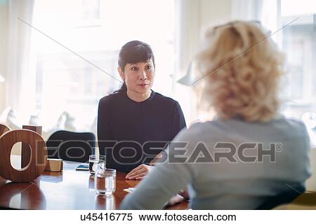 Stock Photography - Mature businesswoman interviewing candidate at boardroom table. Fotosearch