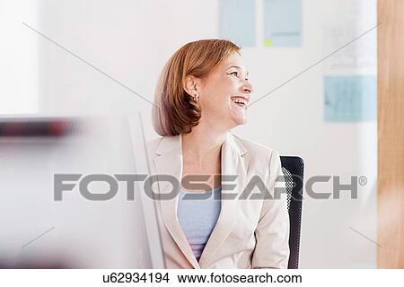 Mature businesswoman laughing at office desk View Large Photo Image Picture - Mature businesswoman laughing at office desk. Fotosearch