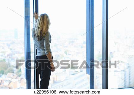 Stock Photograph - "Mature businesswoman looking from office window at Brussels cityscape, Belgium". Fotosearch