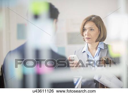 Mature businesswoman meeting with smartphone and blueprints in office View Large Photo Image Stock Photograph - Mature businesswoman meeting with smartphone and blueprints in office. Fotosearch