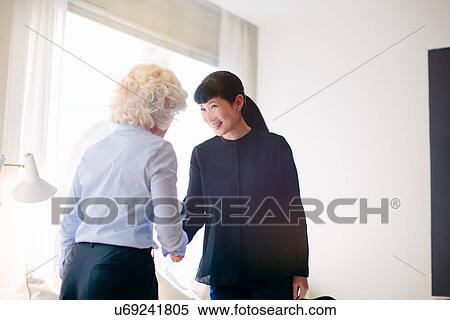 Stock Photography - Mature businesswoman shaking hands with client in office. Fotosearch