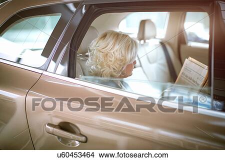 "Mature businesswoman sitting in car, looking through documents" View Large Photo Image Picture - "Mature businesswoman sitting in car, looking through documents". Fotosearch