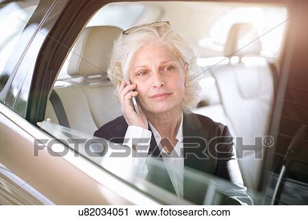 "Mature businesswoman sitting in car, using mobile phone" View Large Photo Image Stock Image - "Mature businesswoman sitting in car, using mobile phone". Fotosearch