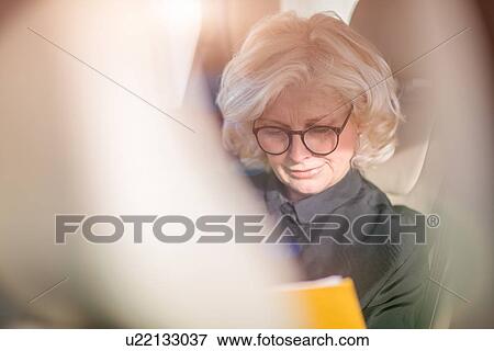 "Mature businesswoman, sitting in car, looking at documents" View Large Photo Image Stock Photo - "Mature businesswoman, sitting in car, looking at documents". Fotosearch