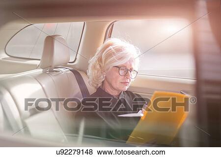 "Mature businesswoman, sitting in car, looking at documents" View Large Photo Image Stock Photo - "Mature businesswoman, sitting in car, looking at documents". Fotosearch