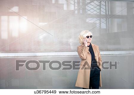 "Mature businesswoman, standing outside building, using mobile phone" View Large Photo Image Stock Photo - "Mature businesswoman, standing outside building, using mobile phone". Fotosearch