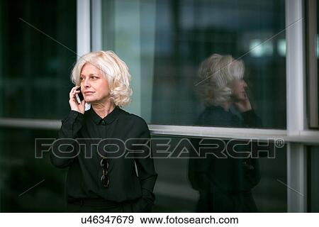 "Mature businesswoman, standing outside building, using mobile phone" View Large Photo Image Stock Photo - "Mature businesswoman, standing outside building, using mobile phone". Fotosearch