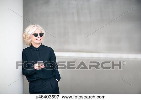 "Mature businesswoman standing outside building, holding smartphone" View Large Photo Image Stock Photo - "Mature businesswoman standing outside building, holding smartphone". Fotosearch