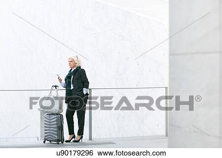 Mature businesswoman standing with luggage View Large Photo Image Stock Photograph - Mature businesswoman standing with luggage. Fotosearch