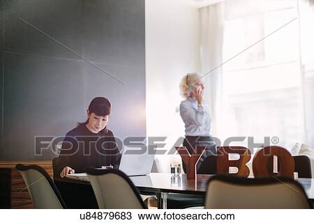 Mature businesswoman using laptop at boardroom table whilst colleague using smartphone View Large Photo Image Stock Image - Mature businesswoman using laptop at boardroom table whilst colleague using smartphone. Fotosearch