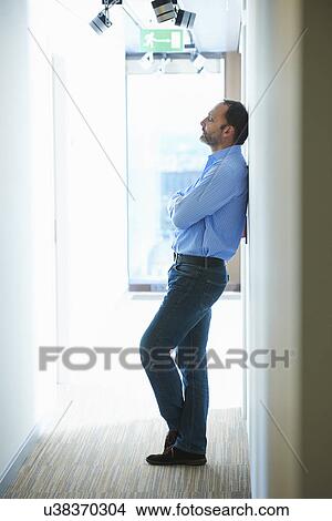 Mature man leaning against wall in corridor View Large Photo Image Picture - Mature man leaning against wall in corridor. Fotosearch
