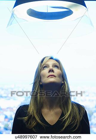 Mature woman looking up into ceiling light View Large Photo Image Stock Photo - Mature woman looking up into ceiling light. Fotosearch