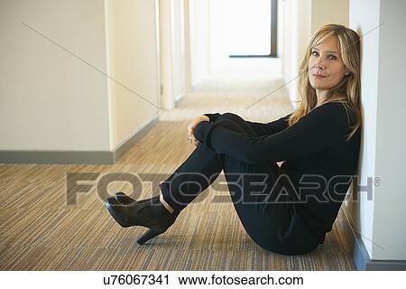 Mature woman sitting against wall in corridor View Large Photo Image Stock Image - Mature woman sitting against wall in corridor. Fotosearch