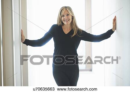 Stock Image - Mature woman standing in corridor. Fotosearch