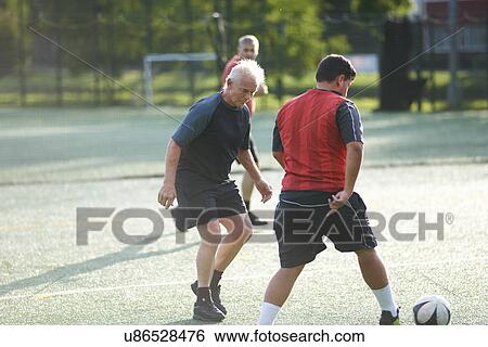 Stock Photograph - Men playing football. Fotosearch