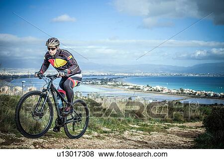 "Mid adult male mountain biker on uphill coastal path, Cagliari, Sardinia, Italy" View Large Photo Image Stock Photo - "Mid adult male mountain biker on uphill coastal path, Cagliari, Sardinia, Italy". Fotosearch