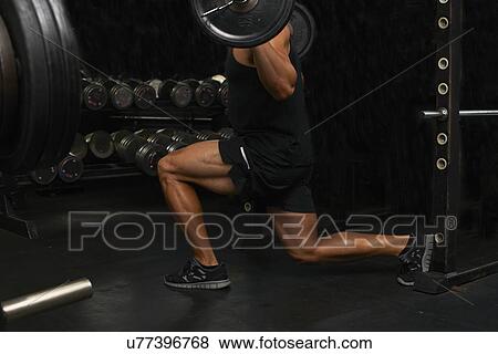 Stock Photo - "Mid adult man, lifting weights, low section". Fotosearch