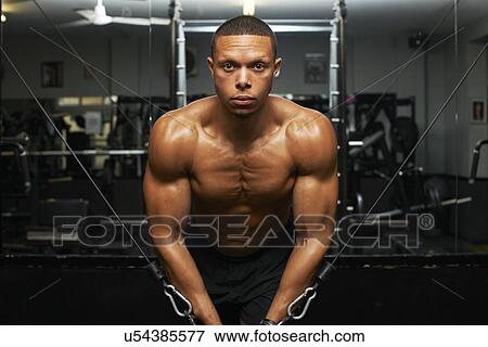 Stock Photo - "Mid adult man, lifting weights, rear view". Fotosearch