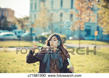 Mid adult woman blowing bubbles in park View Large Photo Image Stock Image - Mid adult woman blowing bubbles in park. Fotosearch