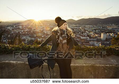 Stock Photo - "Mid adult woman by wall overlooking Graz, Styria, Austria". Fotosearch