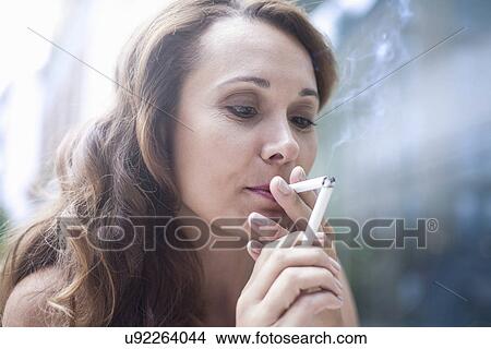 Mid adult woman lighting cigarette from lit cigarette View Large Photo Image Picture - Mid adult woman lighting cigarette from lit cigarette. Fotosearch