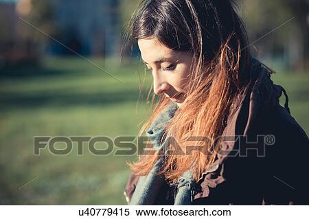 Mid adult woman looking down in park View Large Photo Image Stock Photography - Mid adult woman looking down in park. Fotosearch