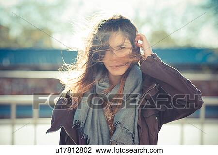 Mid adult woman standing on breezy roadside with hand in hair View Large Photo Image Stock Image - Mid adult woman standing on breezy roadside with hand in hair. Fotosearch