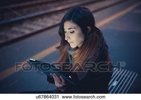 Mid adult woman using digital tablet on railway platform at dusk View Large Photo Image Stock Image - Mid adult woman using digital tablet on railway platform at dusk. Fotosearch