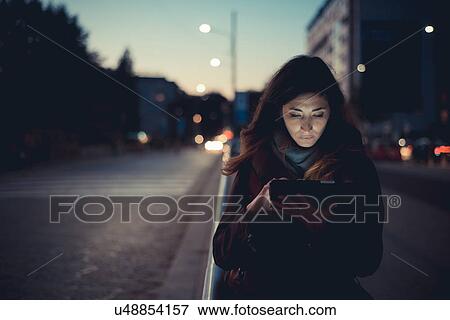 Mid adult woman using digital tablet on street at dusk View Large Photo Image Stock Photo - Mid adult woman using digital tablet on street at dusk. Fotosearch