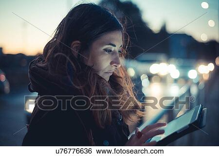 Mid adult woman using digital tablet touchscreen on street at dusk View Large Photo Image Stock Photograph - Mid adult woman using digital tablet touchscreen on street at dusk. Fotosearch