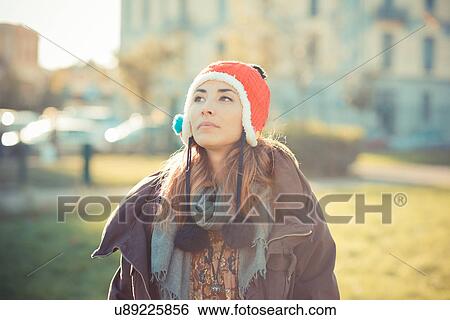 Stock Photograph - Mid adult woman wearing red pom pom hat in park. Fotosearch