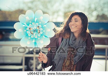 Stock Image - Mid adult woman with flower windmill. Fotosearch