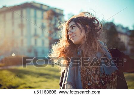 Stock Photograph - Mid adult woman with flyaway hair in breezy park. Fotosearch