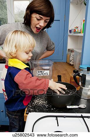 Stock Image - Mother and son making porridge in kitchen. Fotosearch