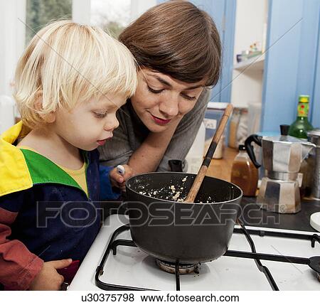 Stock Photo - Mother and son waiting for porridge to cook in kitchen. Fotosearch