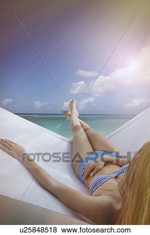 Stock Photo - "Over the shoulder view of young woman reclining on hammock on Miami Beach, Florida, USA". Fotosearch