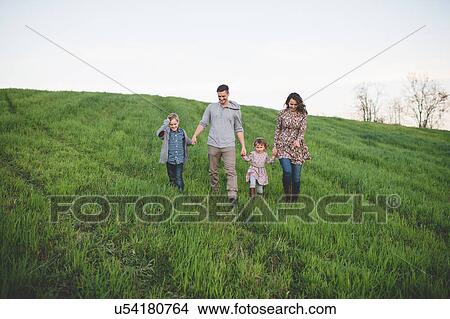 Parents with son and daughter strolling in grassy field View Large Photo Image Picture - Parents with son and daughter strolling in grassy field. Fotosearch