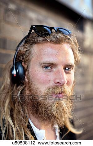 Portrait of bearded young man with headphones and sunglasses View Large Photo Image Stock Image - Portrait of bearded young man with headphones and sunglasses. Fotosearch