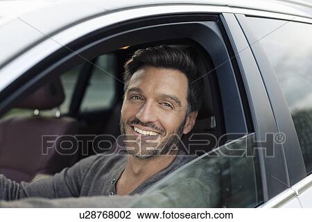 Stock Image - Portrait of handsome mature man looking out of car window. Fotosearch
