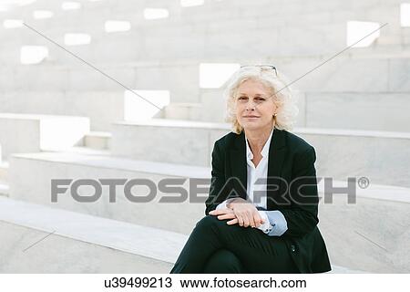 Stock Image - Portrait of mature businesswoman sitting on step. Fotosearch